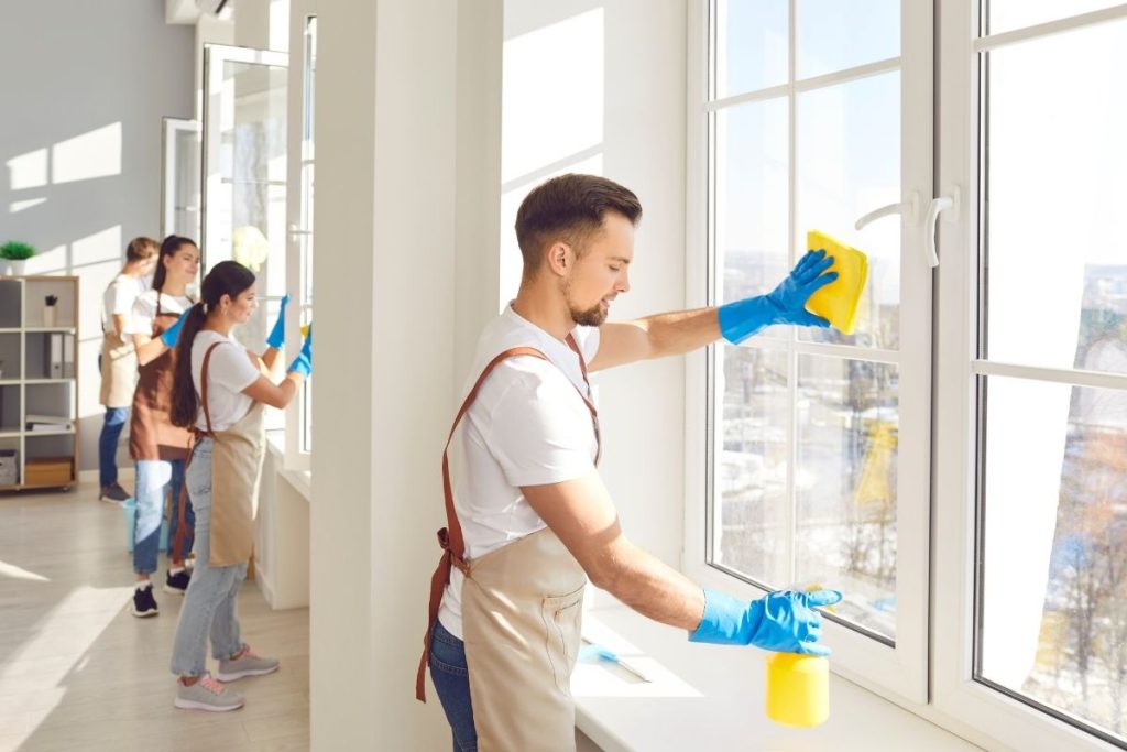 A group of individuals cleaning office windows, using tools and equipment for a thorough cleaning process.
