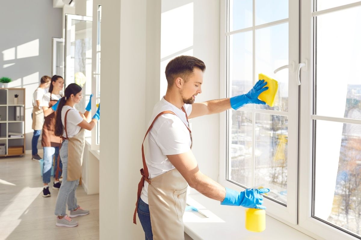 A group of individuals cleaning office windows, using tools and equipment for a thorough cleaning process.