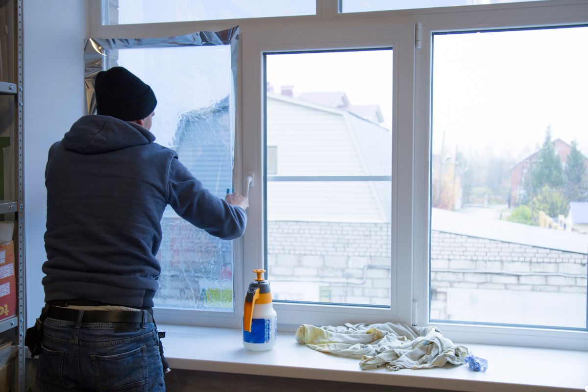 A man using a window cleaner to clean a large window, focused on achieving a streak-free finish.